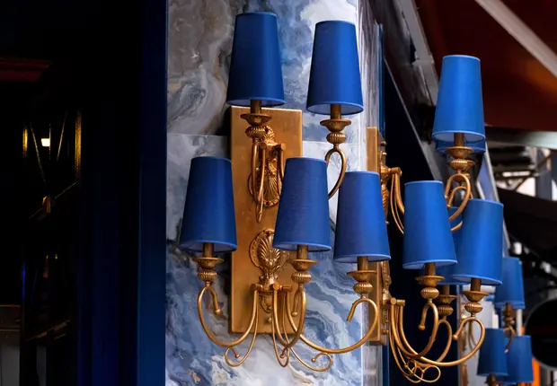 A row of blue shaded wall lights against a marble wall.